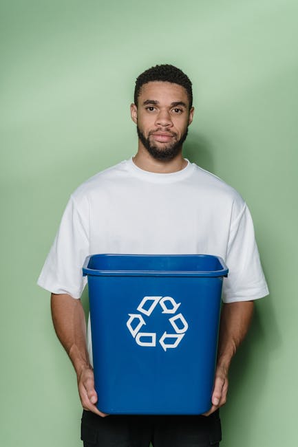 Close-up image of transparent plastic recycling bins placed on a light-colored carpeted floor inside a property. The bins are marked with green recycling symbols on the side and have labels indicating